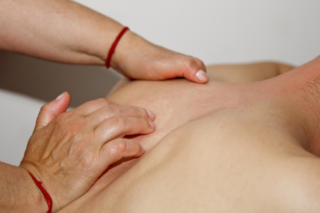Massagem terapêutica profissional das costas e pescoço, a médica massageia um atleta homem em uma sala de massagem corporal e procedimento de cuidados de saúde para recuperação da dor após exercícios esportivos