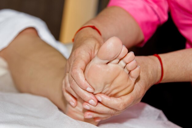 Massagem terapêutica profissional nos pés O médico da mulher massageia o atleta em uma sala de massagem corporal e procedimento de recuperação de dor de cuidados de saúde