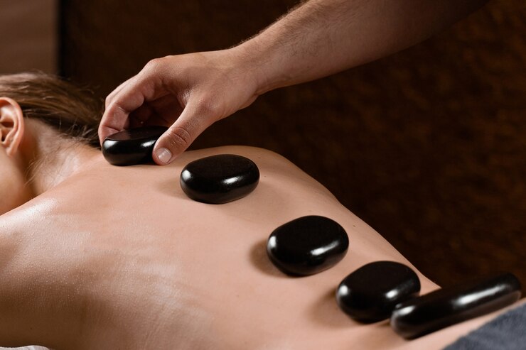 Massagista colocou pedra quente nas costas da mulher. Terapia manual em spa.