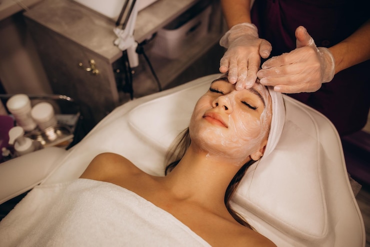 Foto massagista fazendo massagem facial a uma jovem mulher em mesa de massagem em fundo branco conceito de tratamentos de spa de massagem closeup foto de alta qualidade