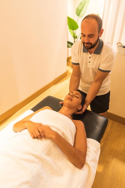 Massagista masculino realizando uma massagem na mesa para uma cliente feminina no pescoço