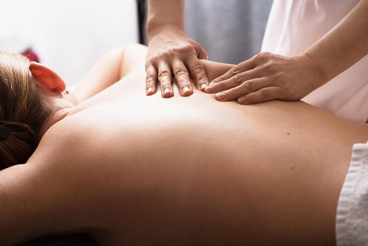 Massagista massageando as costas e as omoplatas de uma jovem na mesa de massagem Conceito de tratamentos de spa de massagem Closeup