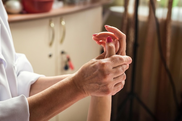 Foto massagista massageando mãos e dedos femininos no salão spa close-up