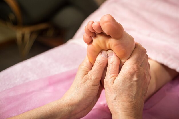 Massagista massageia pés e dedos femininos no spa close-up