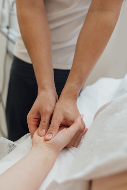 Massagista profissional faz massagem corporal corretiva nos dedos e mãos de uma mulher no salão spa