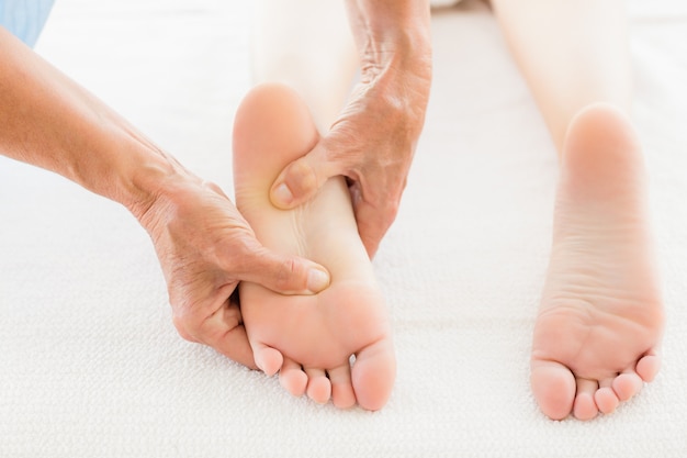 Massagista recortada dando massagem nos pés para mulher