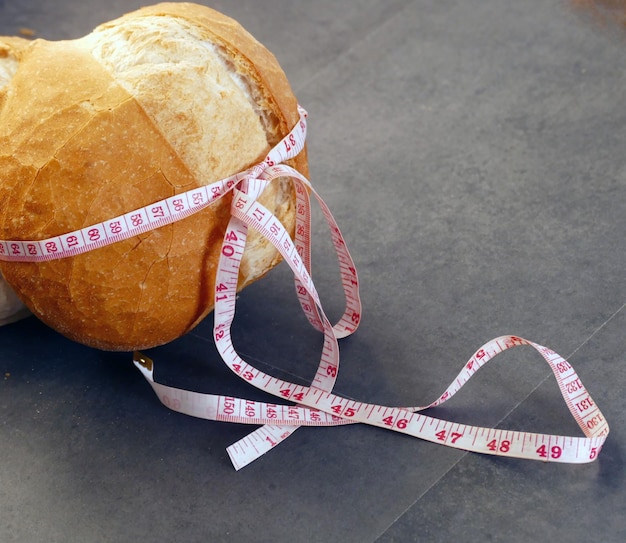 Maßband für Fettleibigkeit und Vollkornbrot, eingewickelt in ein großes Brot