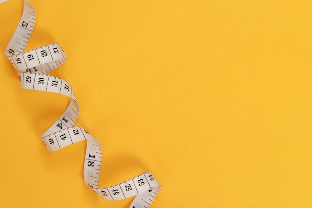 Maßband für übergewichtige Menschen auf gelbem Hintergrund weicher Fokus