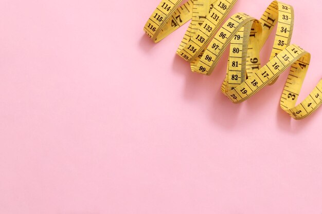 Maßband für übergewichtige Menschen auf rosa Hintergrund weicher Fokus
