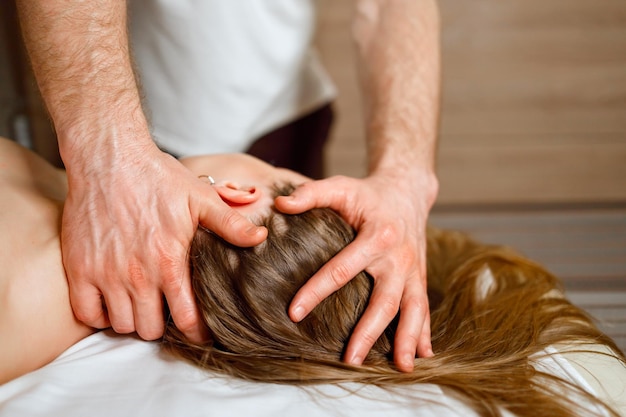 Masseur, der im Spa eine Massage an Hals und Kopf der Frau durchführt