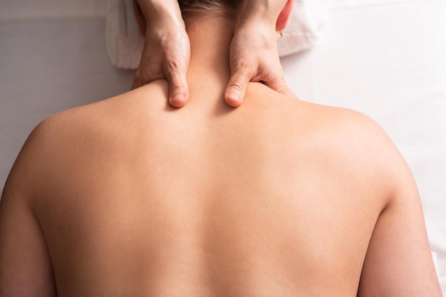 Masseur massiert Rücken und Schulterblätter einer jungen Frau auf einem Massagetisch Konzept der Massage-Spa-Behandlungen Nahaufnahme
