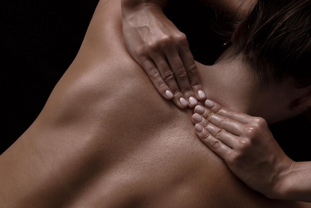 Masseurmädchen macht eine Massagenahaufnahme auf einem dunklen Hintergrund Nahaufnahmemassage