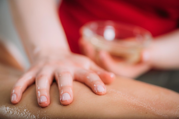 Massieren mit Massageölhänden einer Massagetherapeutin, die eine Klientin massiert