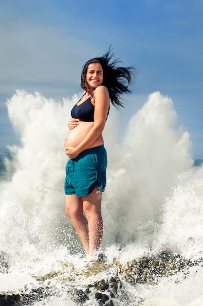 Massiver Spritzer Wasser hinter einer glücklichen schwangeren Frau