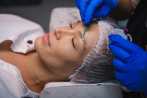 Foto master aplica pasta para cejas con un pincel en las cejas