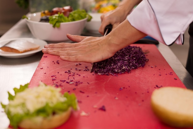 Master chef cortando ensalada para una hamburguesa en la cocina rastaurant