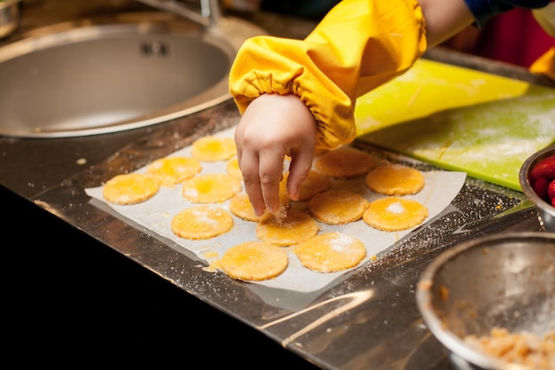 Foto master class para crianças em cozinhar biscoitos. uma criança passa manteiga em um biscoito para assar