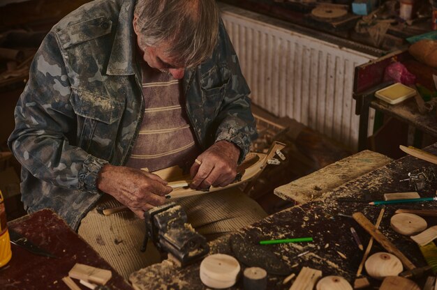 Foto master-class sobre fabricação de brinquedos de madeira. mãos de um mestre de escultura em madeira com um cinzel e uma peça de madeira.