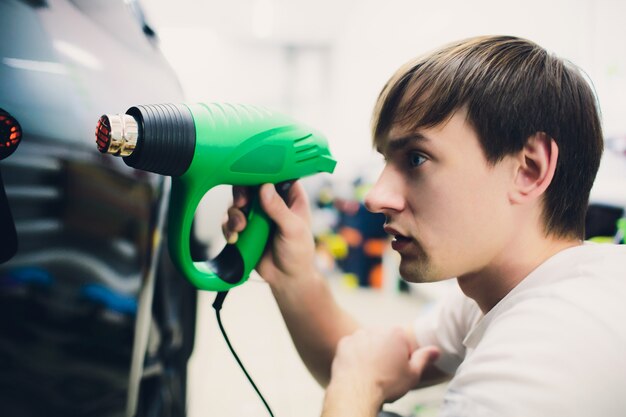 Master instala filme matiz para carro com secador de cabelo. Carro de proteção de conceito