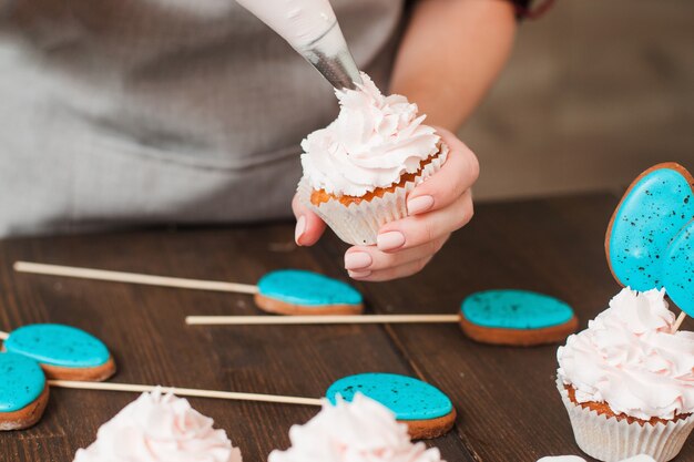 Masterclass de preparación de cupcakes con crema blanca en mesa de madera