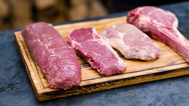 Masterclasse de culinária. Cortes frescos, variedade de carne bovina crua na placa de madeira.