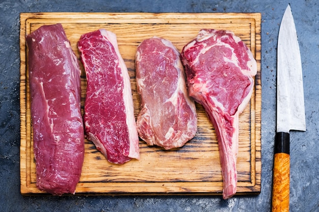 Masterclasse de culinária. Receita de bife. Variedade de carne crua de carne na placa de madeira e na faca.