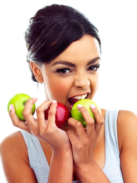 Masticando cosas saludables Retrato de estudio de una mujer joven en ropa de gimnasia sosteniendo manzanas