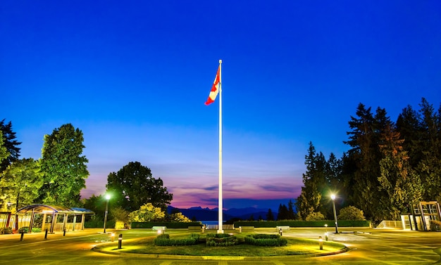 El mástil de la bandera con una bandera canadiense en la Universidad de Columbia Británica en Vancouver al atardecer