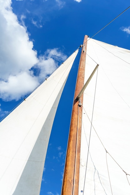 Foto mástil de un velero con equipo de vela bermuda contra un cielo azul, vista de abajo hacia arriba