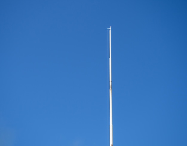 Mastro branco vazio contra o céu azul Bandeira abaixada