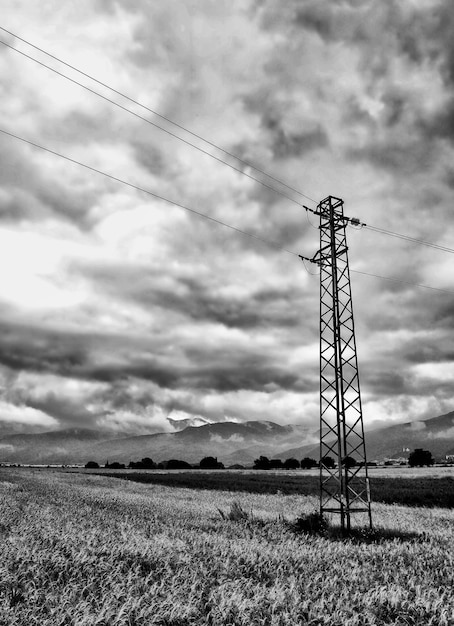 Foto mastro de eletricidade no campo contra o céu nublado