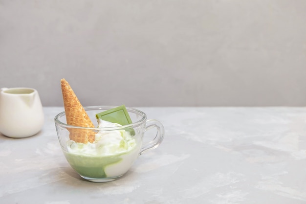 Matcha-Affogato-Rezept mit Vanilleeis und gesundem Matcha-Grüntee in einer Glasschale auf grauem Tisch