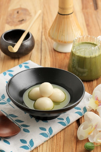 Matcha Big Tangyuan Tang Yuan con sopa de Matcha dulce en un tazón de madera sobre fondo de mesa de madera negra para la comida del festival Solsticio de invierno