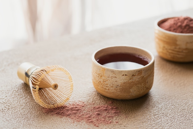 Matcha de chá em pó de cor orgânica com batedeira de bambu de ferramentas japonesas em fundo bege. Conceito de bebida saudável vegetariana, bebida