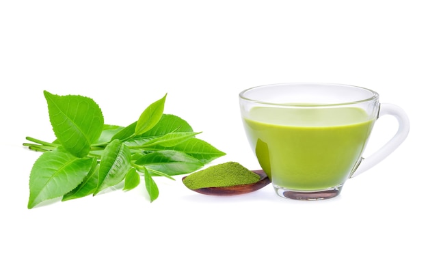 Matcha latte de té verde caliente con té verde en polvo y hojas de té aisladas sobre fondo blanco.