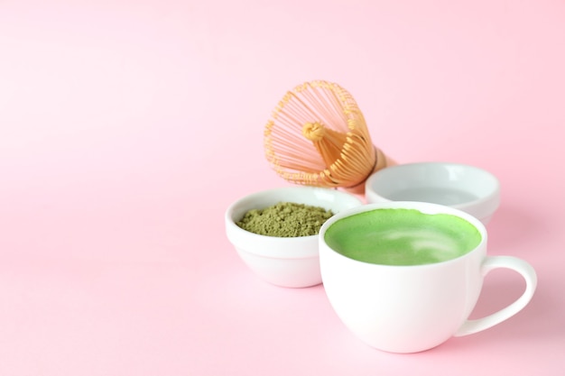 Matcha Latte und Zubehör für die Zubereitung auf rosa Hintergrund