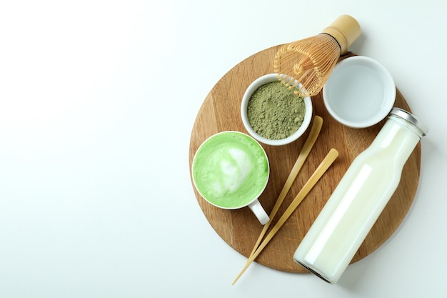 Matcha Latte und Zubehör für die Zubereitung auf weißem Hintergrund