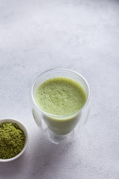 Matcha con leche en un vaso sobre un fondo claro