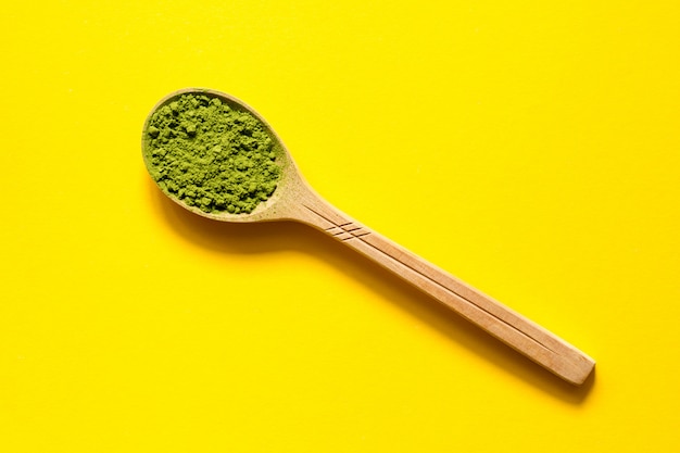 Foto matcha. té verde pulverizado japonés en una cuchara en un fondo amarillo.