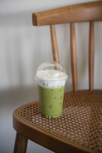 Foto matcha té verde en una taza de plástico en otra silla de madera vintage en una cafetería