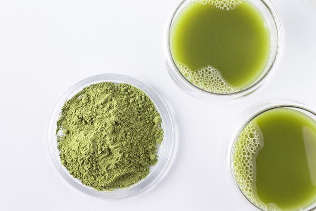 Matcha-Tee in Glasbechern auf weißem Hintergrund flach