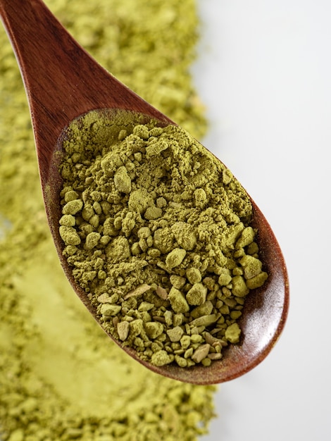 Matcha-Teepulver von grüner Farbe wird auf einem weißen Hintergrund verstreut. Platz kopieren.