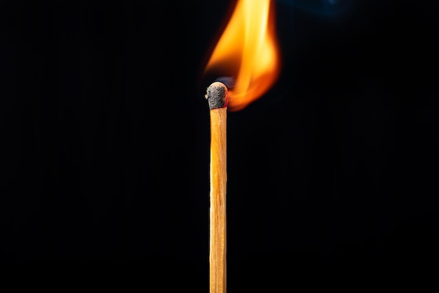 Matchstick queimando em detalhes visto através de um foco seletivo de fundo preto de lente macro
