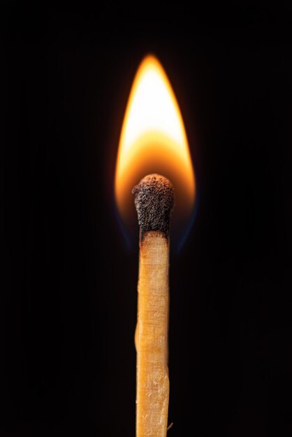 Matchstick queimando em detalhes visto através de um foco seletivo de fundo preto de lente macro