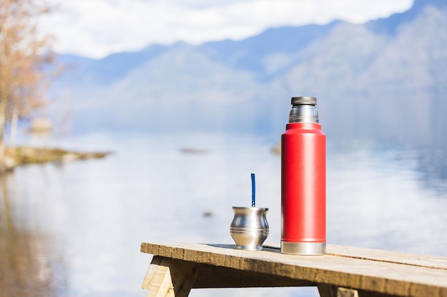 Mate y un termo lleno de agua listo para beber en un lugar tranquilo del lago