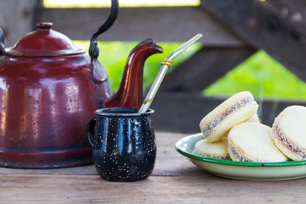 Mate y tetera con un plato de infusión de alfajores e yerba mate en el campo argentino