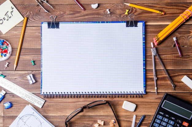 Material del alumno con cuaderno para texto en la mesa de madera.