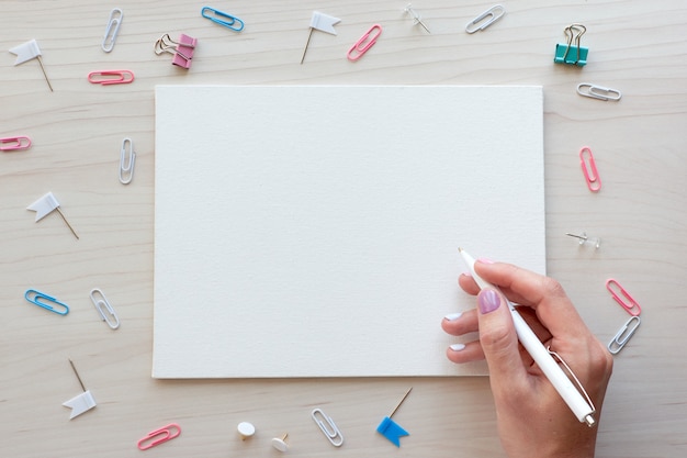 Material de escritório escolar em fundo de madeira. de volta ao conceito de escola. quadro branco com as mãos para espaço de cópia. vista superior pronta para seu projeto.