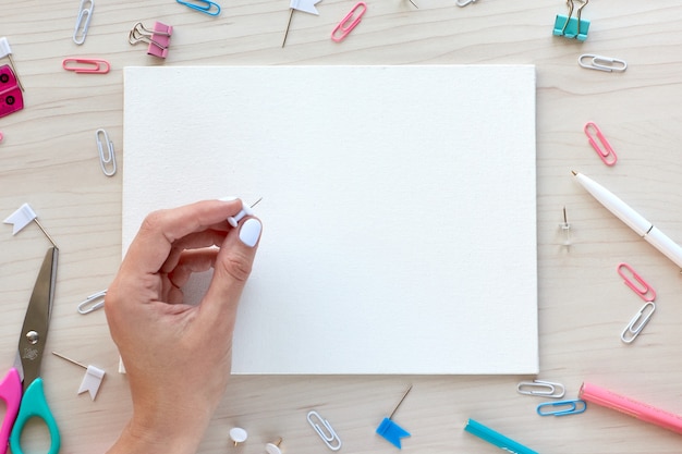 Material de escritório escolar em fundo de madeira. De volta ao conceito de escola. Quadro branco com as mãos para espaço de cópia. Vista superior pronta para seu projeto.