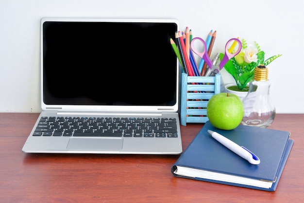 Material de escritório, laptop com notebook e apple na mesa de madeira